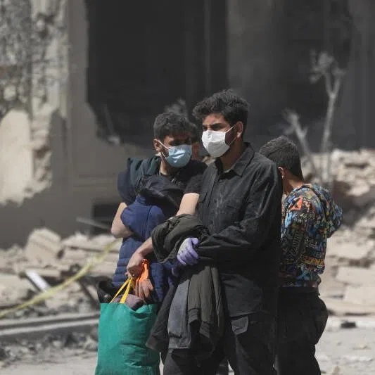 People walk in a residential neighbourhood damaged by a strike in Tehran, Iran.