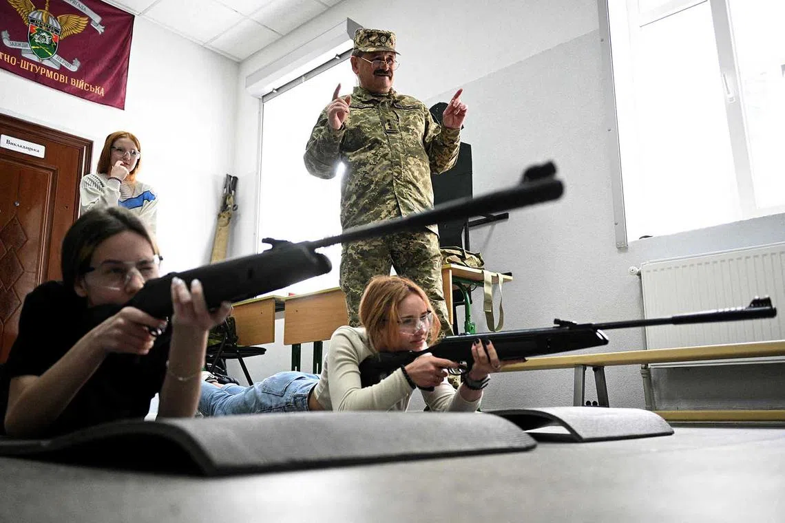 Girls shoot at a target with a pneumatic rifle during a training lesson focused on the "Defence of Ukraine" at the military-patriotic centre for schoolchildren in Lviv on May 17, amid the Russian invasion of Ukraine. 