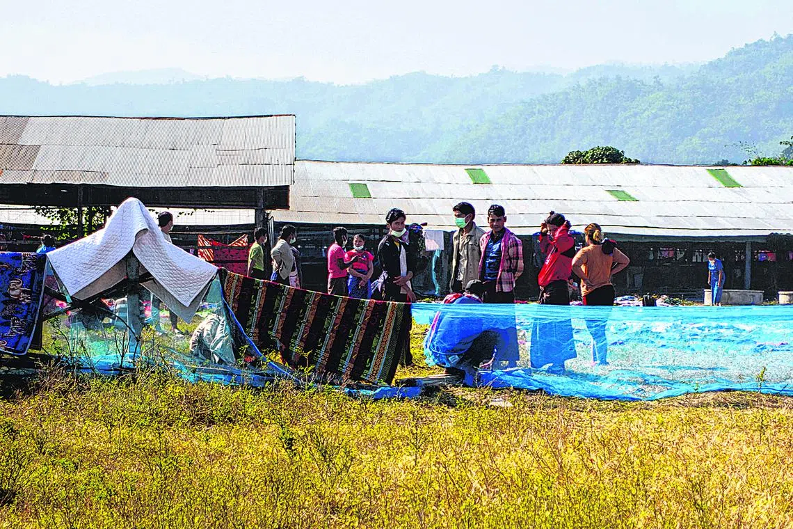 Refugees, who fled a flare-up in fighting between the Myanmar army and ethnic minority rebels, stand at a temporary shelter in Mae Sot district.