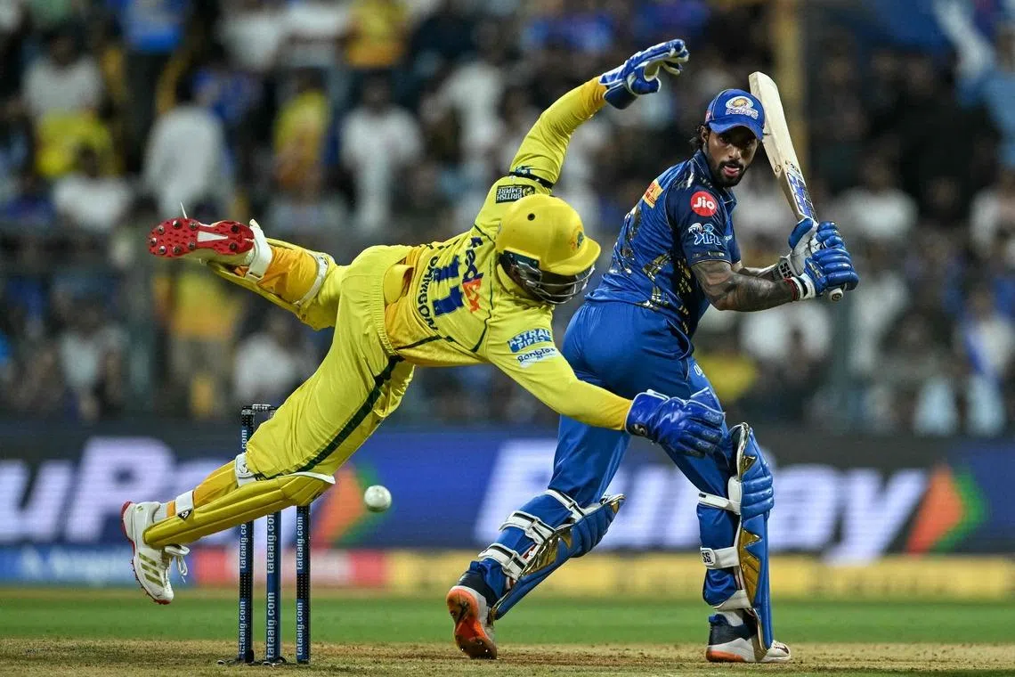 Chennai Super Kings' wicketkeeper Indian cricket player Sanju Samson (L) jumping to field the ball as Mumbai Indians' Indian cricket player Tilak Varma watches during the 2026 Indian Premier League (IPL) T20 match between Mumbai Indians and Chennai Super Kings at the Wankhede Stadium in Mumbai, India on April 23, 2026. 