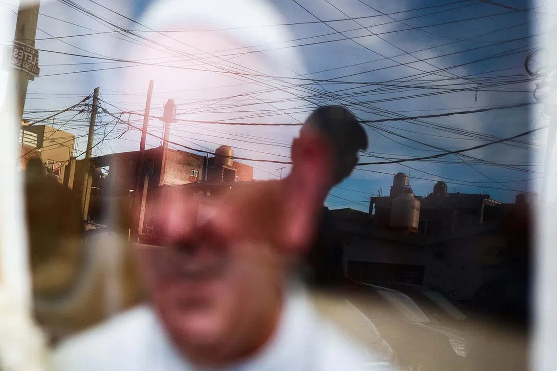 A person is reflected in a picture of Pope Francis placed outside the Virgen de Caacupe chapel, following the death of the pontiff, in Buenos Aires, Argentina, April 21, 2025. 