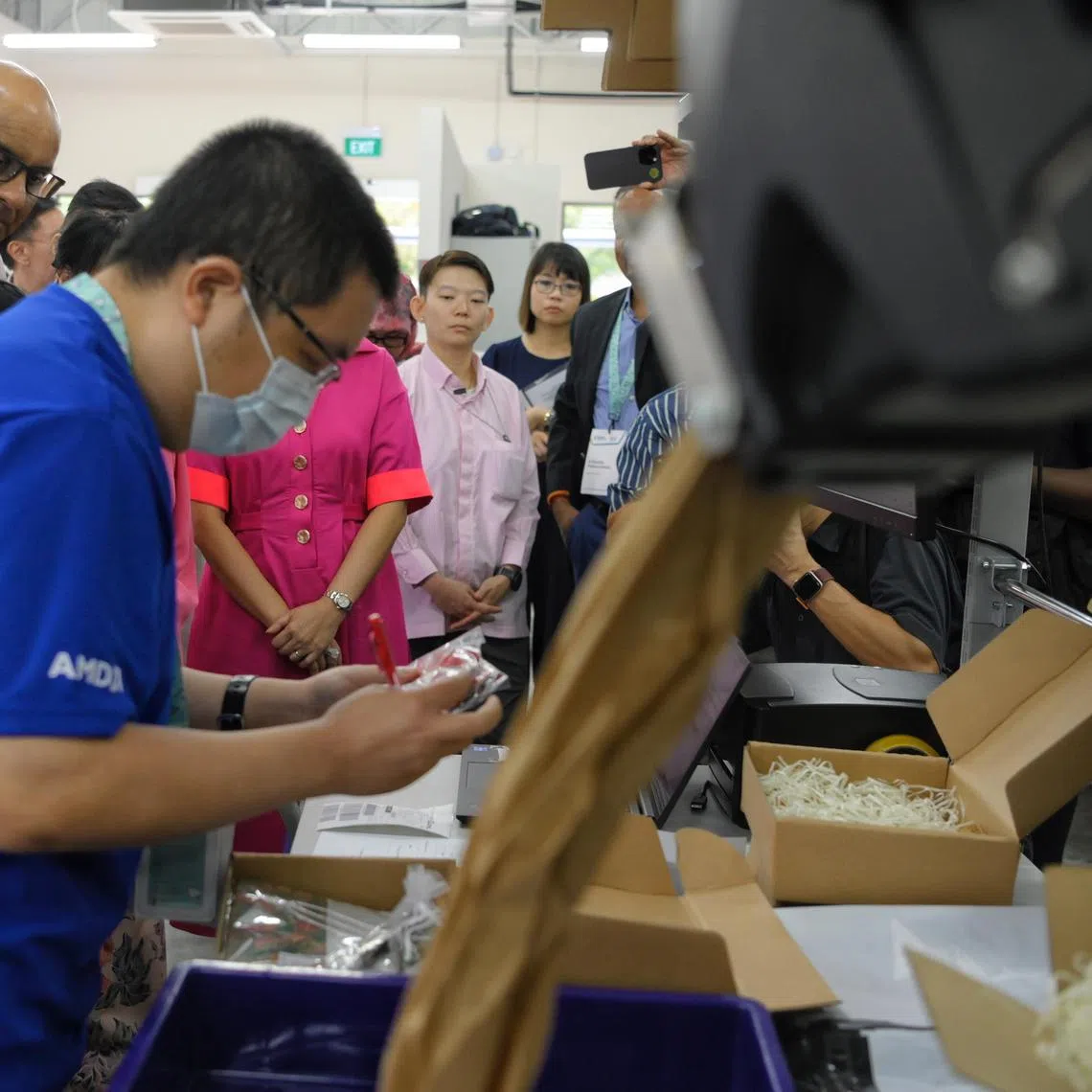 President Tharman Shanmugaratnam (left) watches as Bizlink Centre Singapore trainee Chan Yong Shen (foreground), 38, packs parcels at the Enabling Business Hub (EBH) during the opening ceremony on December 13, 2023.