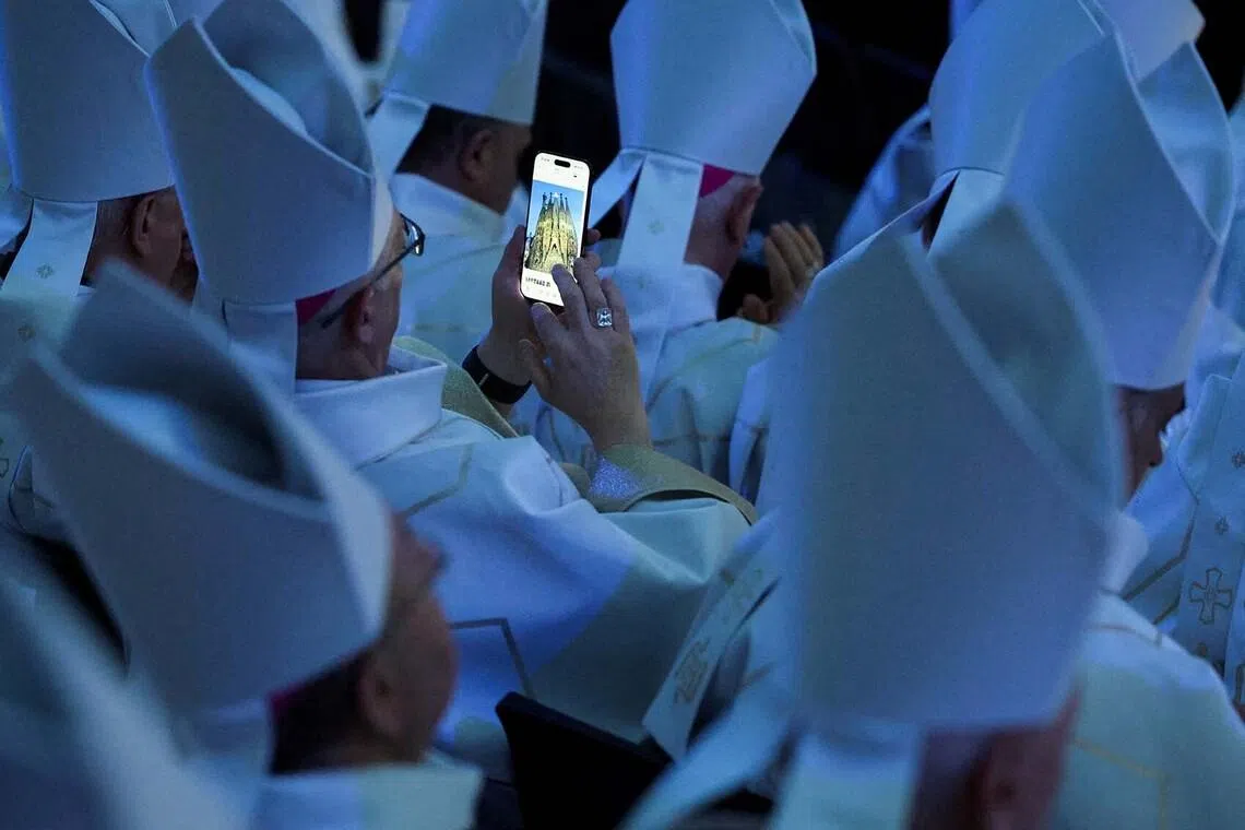 A member of the clergy looking at photographs of the Basilica of the Sagrada Familia on a smartphone on the day the inauguration and blessing of the Tower of Jesus Christ by Pope Leo XIV during his apostolic journey in Barcelona, Spain, June 10.