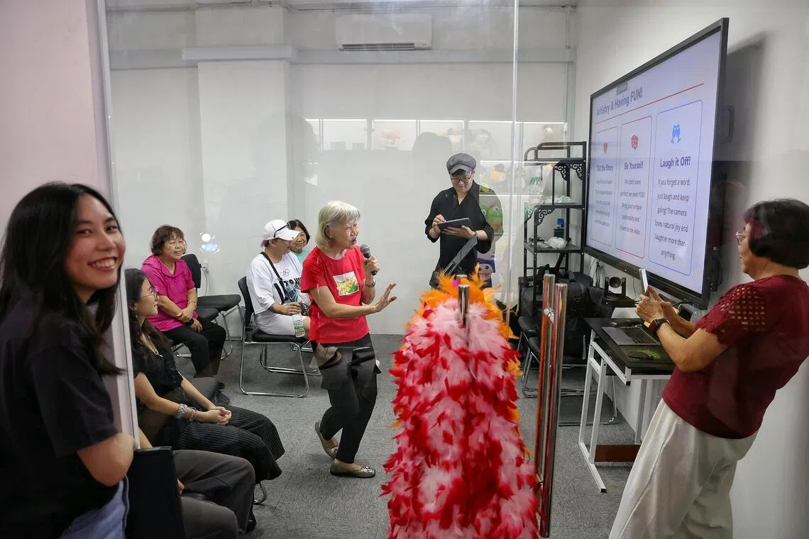 June Lim (left), 24, a Year 3 student in Diploma in Performance at Lasalle College of the Arts, smiling after watching retiree Ellie Teo (in red), 72, go through vocal preparation with vocal coach Jeremy Han (second from right) at social enterprise The WoW Movement on Aug 29, 2026.
