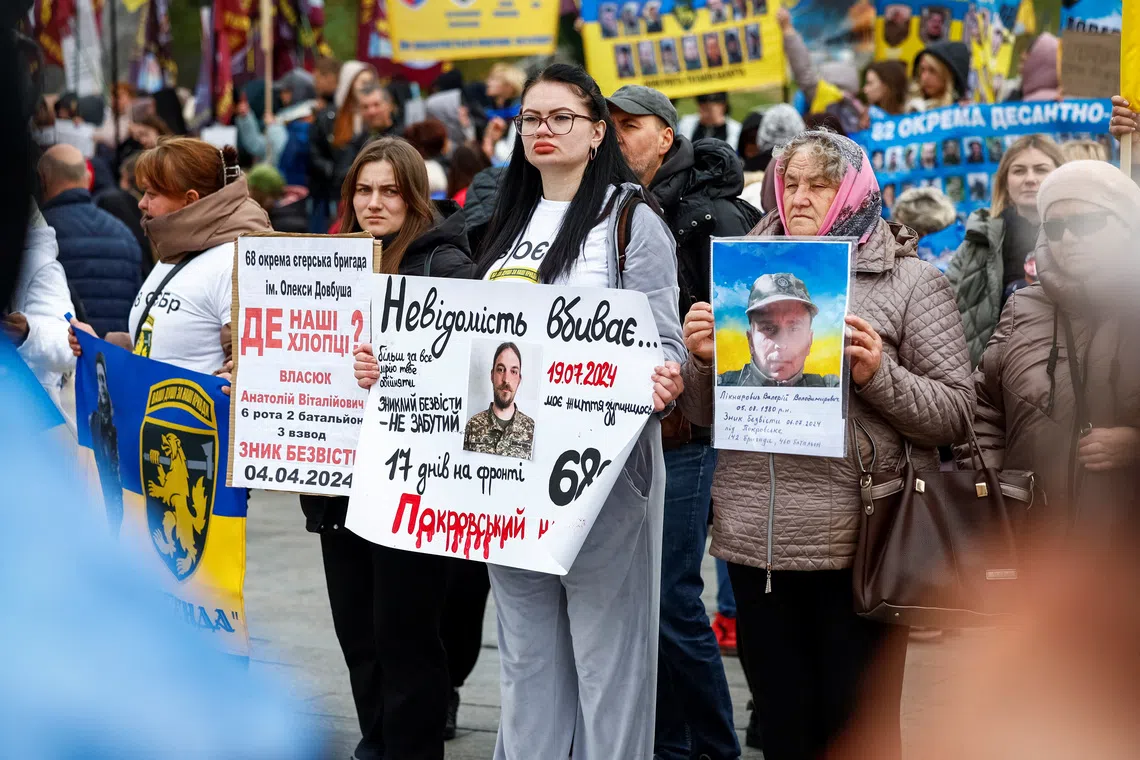 Anastasiia Tsvietkova, 29, wife of a 37-years-old Yaroslav Kochemasov, serviceman of the National Guard of Ukraine, who was declared missing-in-action in Donetsk region, holds a poster with a photo of him as she attends a rally with relatives of missing service members, amid Russia's attack on Ukraine, in Kyiv, Ukraine, October 16, 2024. REUTERS/Alina Smutko