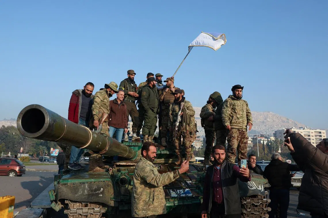 Rebel fighters stand on a tank, after rebels seized the capital and ousted President Bashar al-Assad, in Damascus, Syria, December 9, 2024. REUTERS/Mohamed Azakir