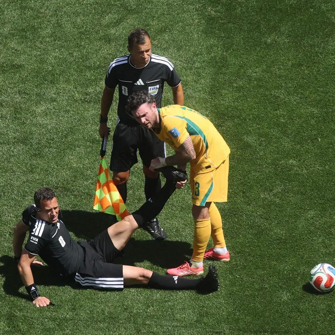 SEATTLE, WASHINGTON - JUNE 19: Referee Felix Zwayer is helped stretching his leg by Aiden O'Neill #13 of Australia after cramping during the FIFA World Cup 2026 Group D match between USA and Australia at Seattle Stadium on June 19, 2026 in Seattle, Washington.   Alex Grimm/Getty Images/AFP (Photo by ALEX GRIMM / GETTY IMAGES NORTH AMERICA / Getty Images via AFP)