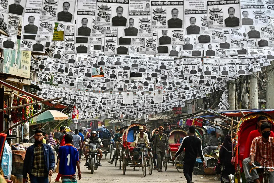 TOPSHOT - Posters of the election candidates are seen hanging over a street ahead of the 2024 general elections, in Dhaka on December 26, 2023. (Photo by Munir UZ ZAMAN / AFP)