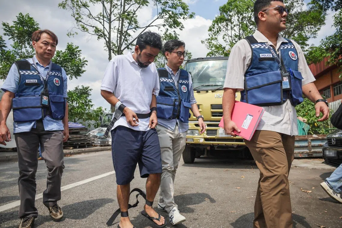 Mohd Mazuan Abdullah being escorted by police officers along Sungei Kadut street 4 to retrace his steps in a vehicle theft and car cloning syndicate in Malaysia, on March 23.