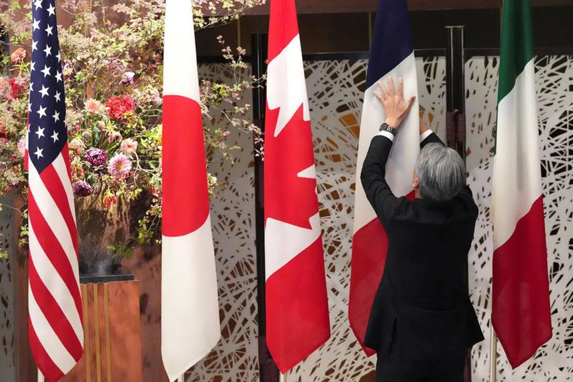 FILE PHOTO: A member of staff arranges national flags prior to a group photo session during the G7 Foreign Ministers' Meeting at the Iikura Guest House Wednesday, Nov. 8, 2023, in Tokyo, Japan. Eugene Hoshiko/Pool via REUTERS