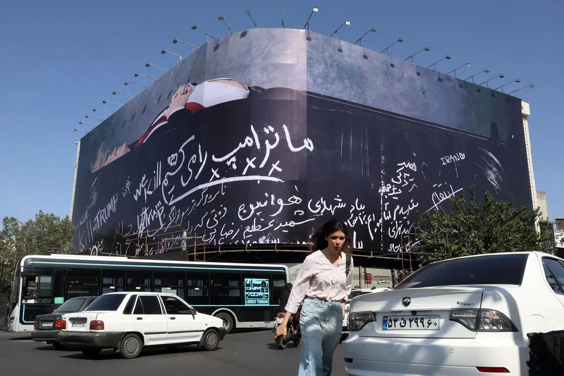 Pedestrians walk next to a huge billboard in Tehran featuring US President Donald Trump in a coffin, accompanied by a sentence in Persian that reads: “We kill Trump”.