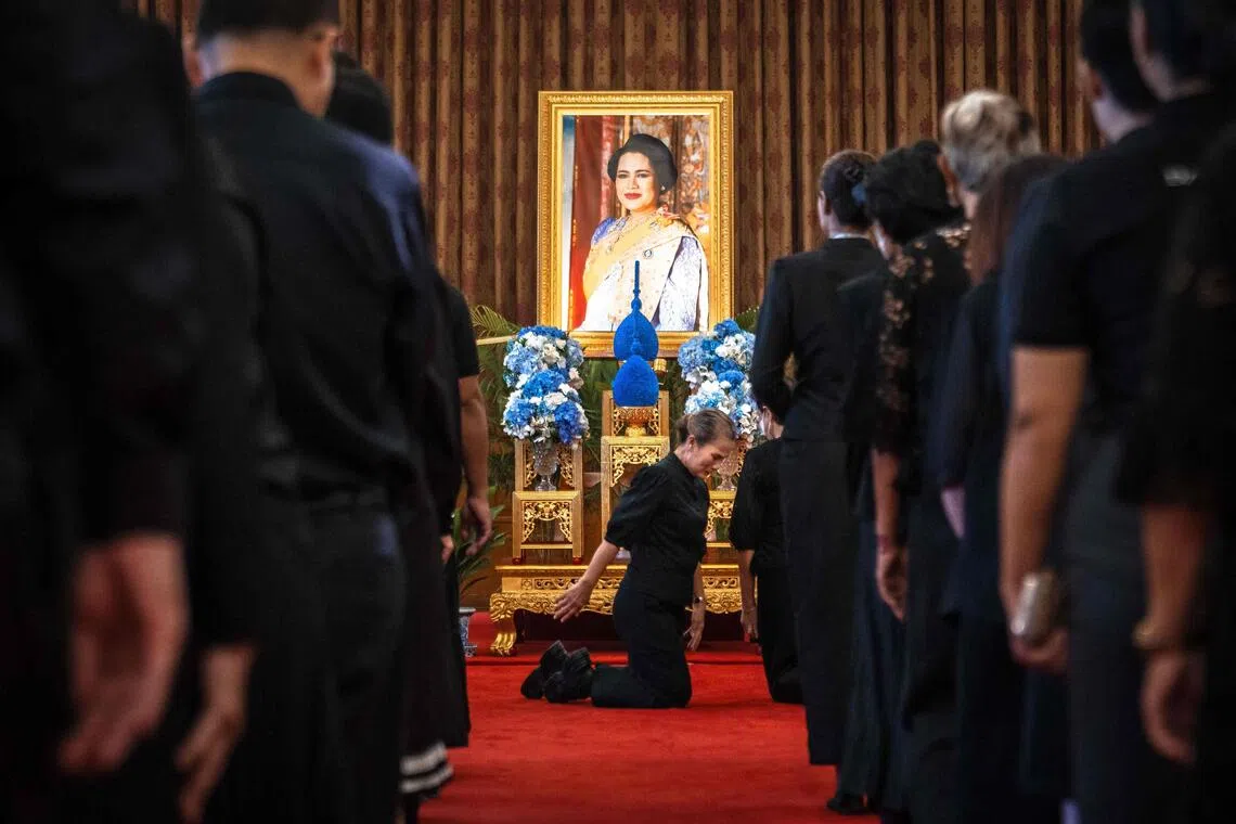 Mourners line up to pay respects in front of a portrait of Thailand's former queen Sirikit inside the Grand Palace in Bangkok on October 26, 2025. The year-long funeral ceremony of Thailand's former Queen Sirikit started October 26, with grieving royalists set to salute the procession bringing her remains to lie in state at Bangkok's Grand Palace. (Photo by Chanakarn Laosarakham / AFP)