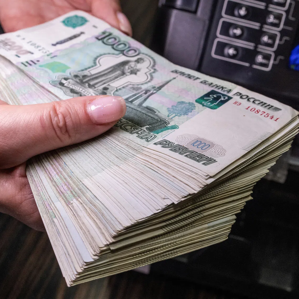 An employee holds Russian 1000-rouble banknotes next to a currency counting machine in a bank office in Moscow, Russia, in this illustration picture taken October 9, 2023. REUTERS/Maxim Shemetov