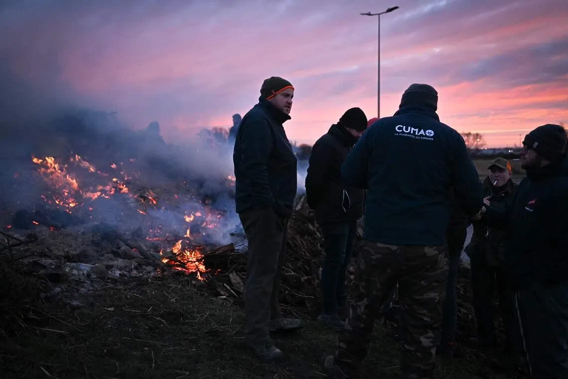 French farmers standing at a roundabout as part of national protests against the EU-Mercosur agreement and the government's handling of the contagious nodular dermatitis (CND) epidemic, on the port of Le Havre, northwestern France, on Jan 11, 2026. 