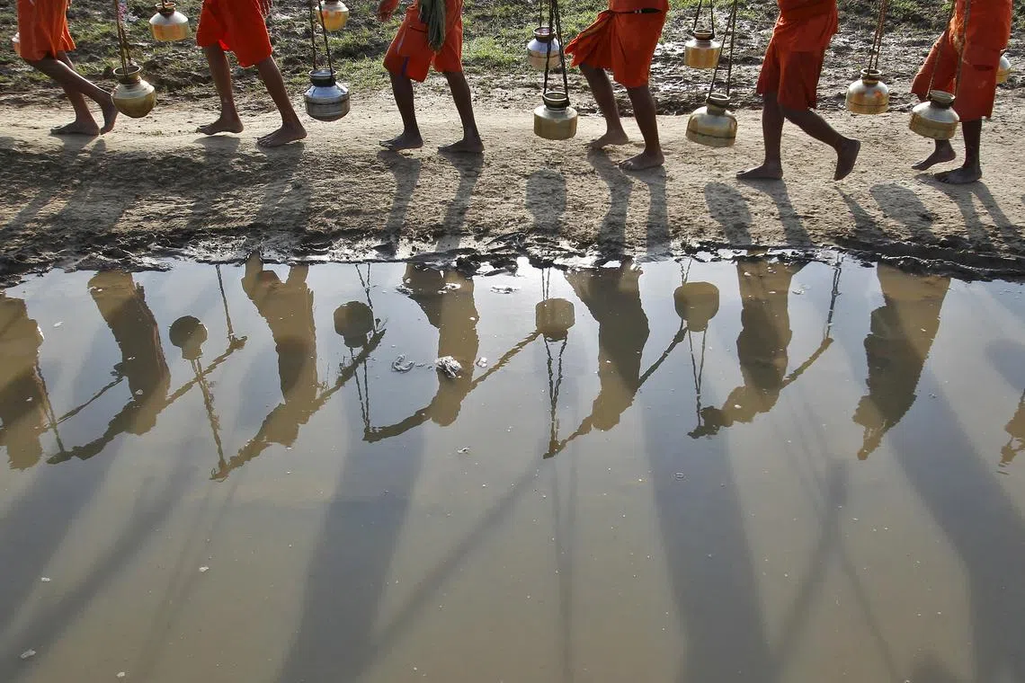 FILE PHOTO: Kanwarias or devotees of Hindu god Shiva carrying pitchers are reflected in a puddle as they walk after filling the pitchers with the water from the river Ganges in Allahabad, India, July 13, 2015. REUTERS/Jitendra Prakash/File Photo