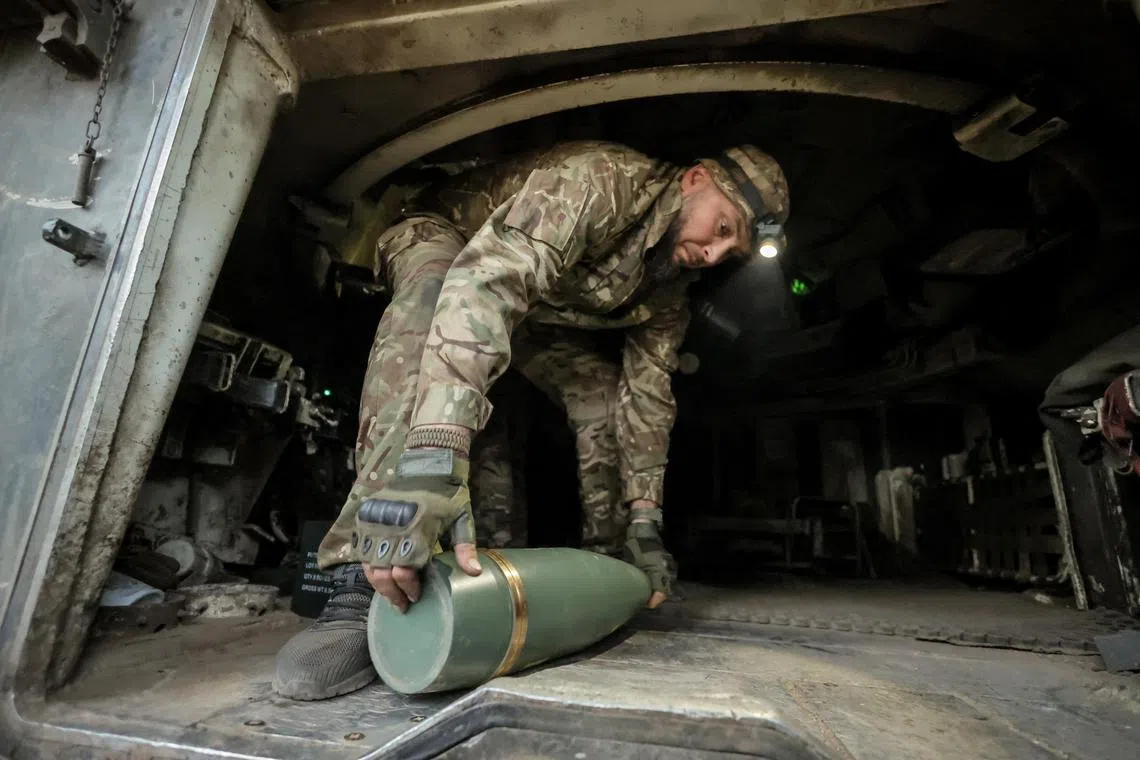 A Ukrainian serviceman carrying a shell to an M109 self-propelled howitzer before firing towards Russian troops, near the front-line town of Chasiv Yar, Ukraine, in June 2025.