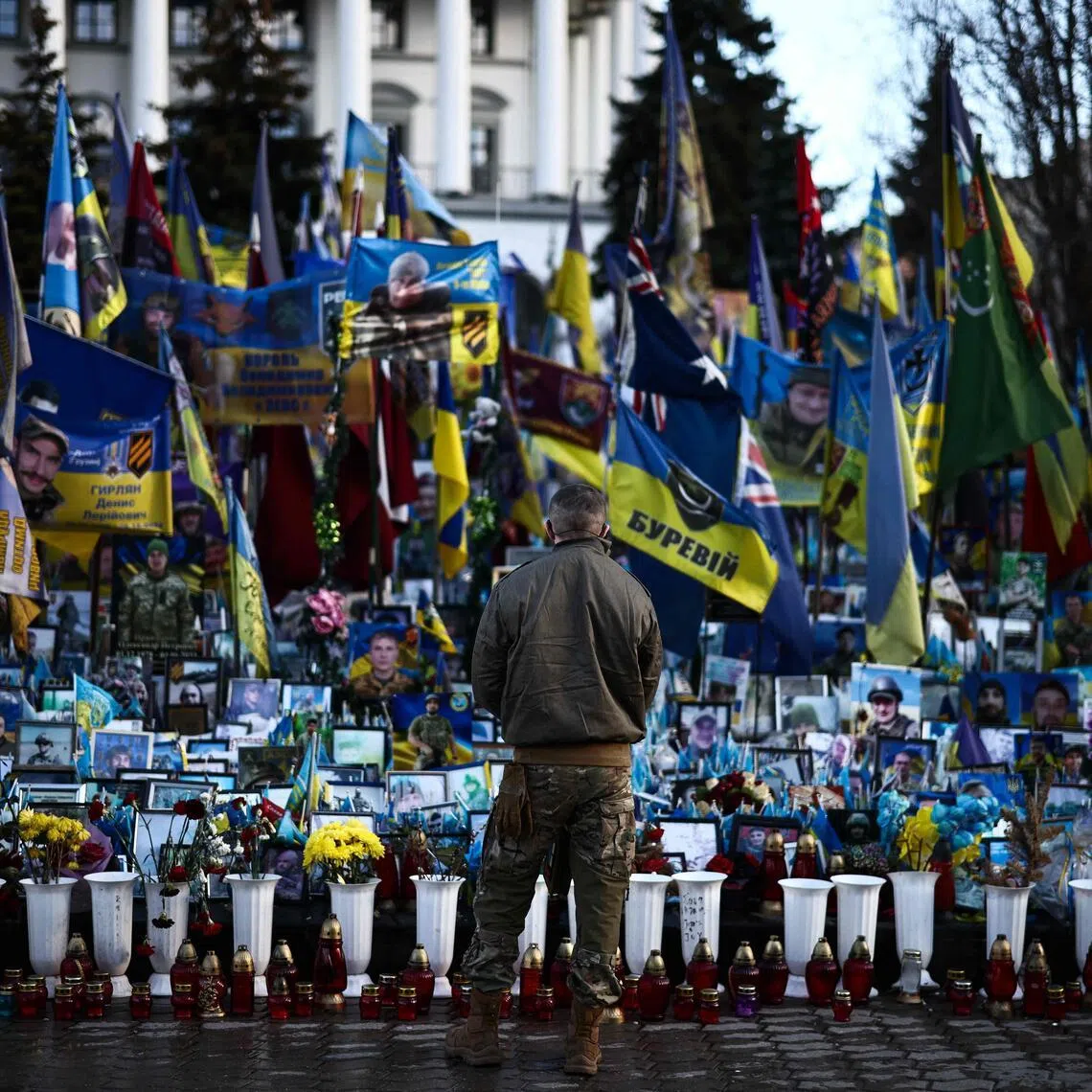 A member of the Ukrainian military visiting  a makeshift memorial to fallen Ukrainian and foreign soldiers, at Independence Square in Kyiv, on March 2.