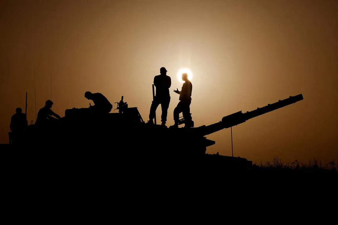 Israeli soldiers standing on a tank, amid the ongoing conflict between Israel and the Palestinian group Hamas, near Israel's border with Gaza in southern Israel, Nov 23, 2023. 