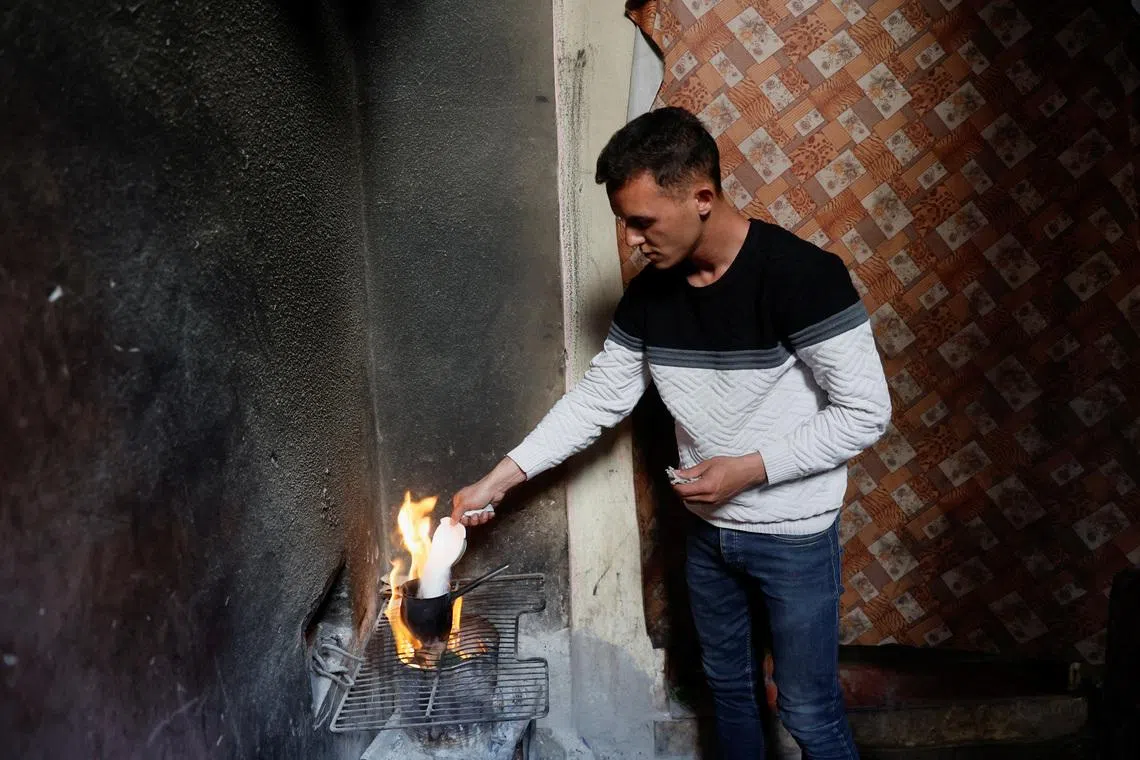 A Palestinian man, Abdul Rahman Al-Shaaf, stands by a fire, heating water in a kettle in Deir al-Balah, central Gaza Strip, April 16, 2026. REUTERS/Haseeb Alwazeer