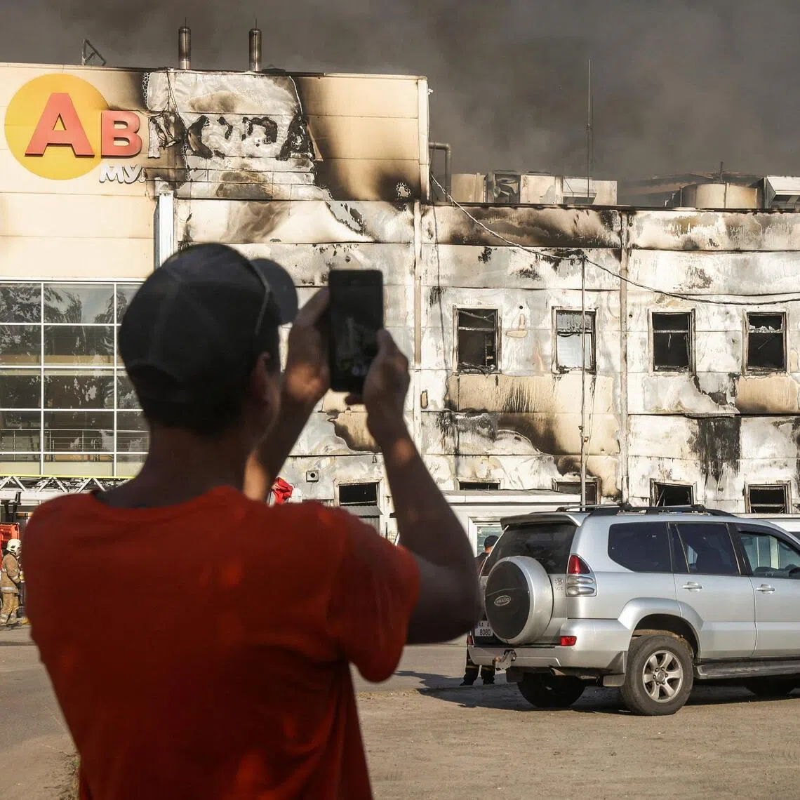 A man taking a photo on Aug 31 of firefighters working at the site of a Russian drone strike on a warehouse in the Kyiv region.