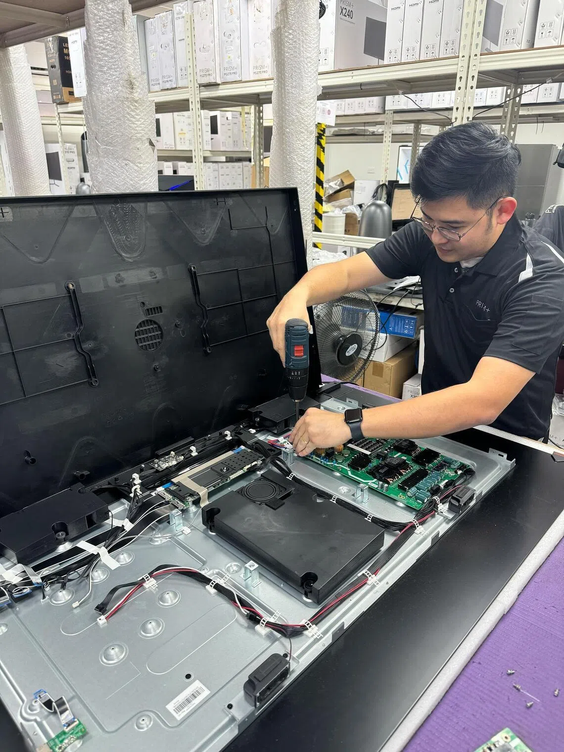 A Prism+ employee conducting a quality check on a television.
