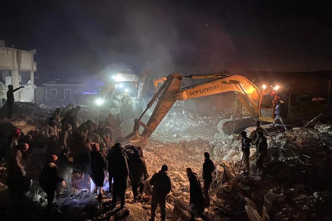 Rescue workers look for survivors amid the rubble of a building in the rebel-held town of Jindayris on Feb 8, 2023.