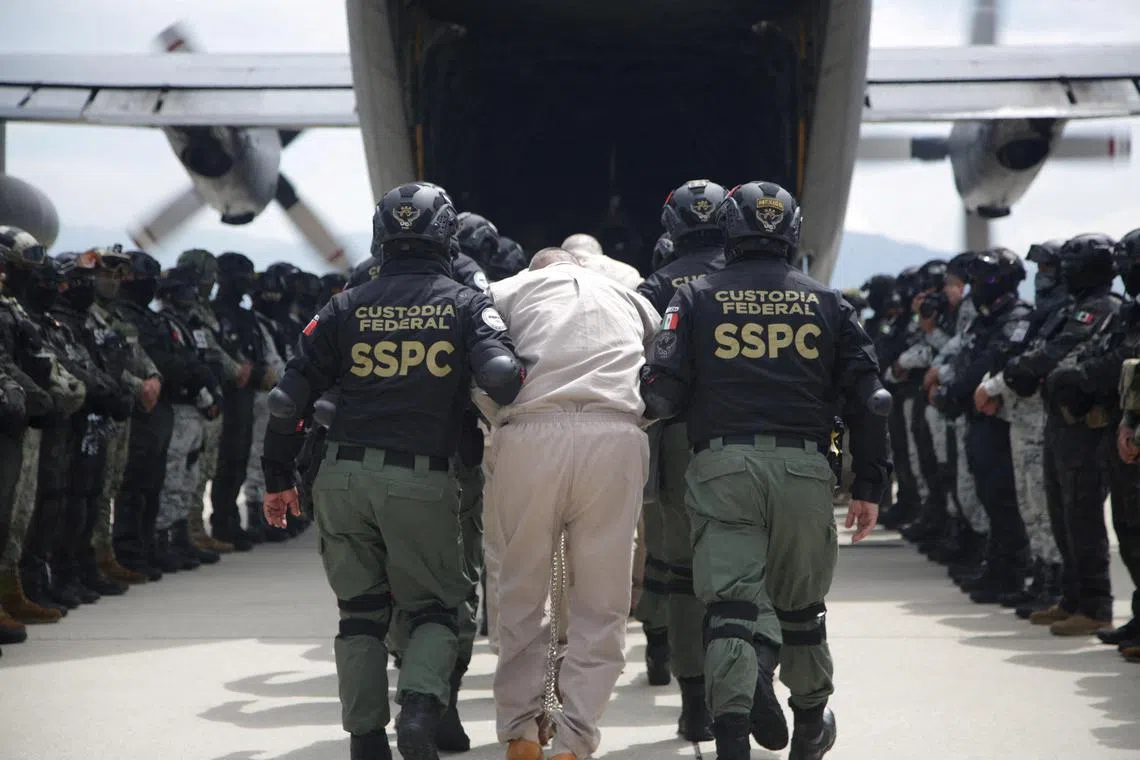 Mexican law enforcement agents escort prisoners wanted in the US for ties to drug-trafficking groups into a plane.