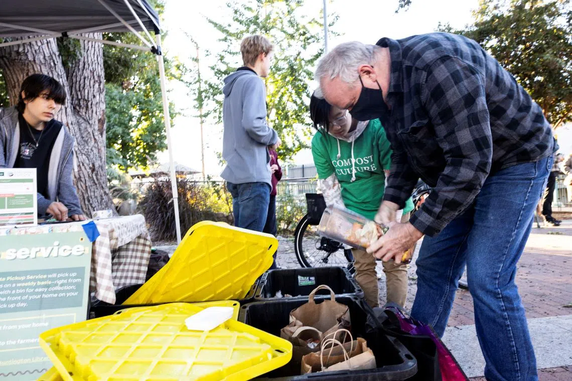 Richard Redmond brings his food scraps to Compost Culture, a high-school students-run organisation that collects food waste to turn it into compost, as Claire Wang and Daniel Freysson look on, at the South Pasadena farmers market, in South Pasadena, California, US, November 3, 2022. 