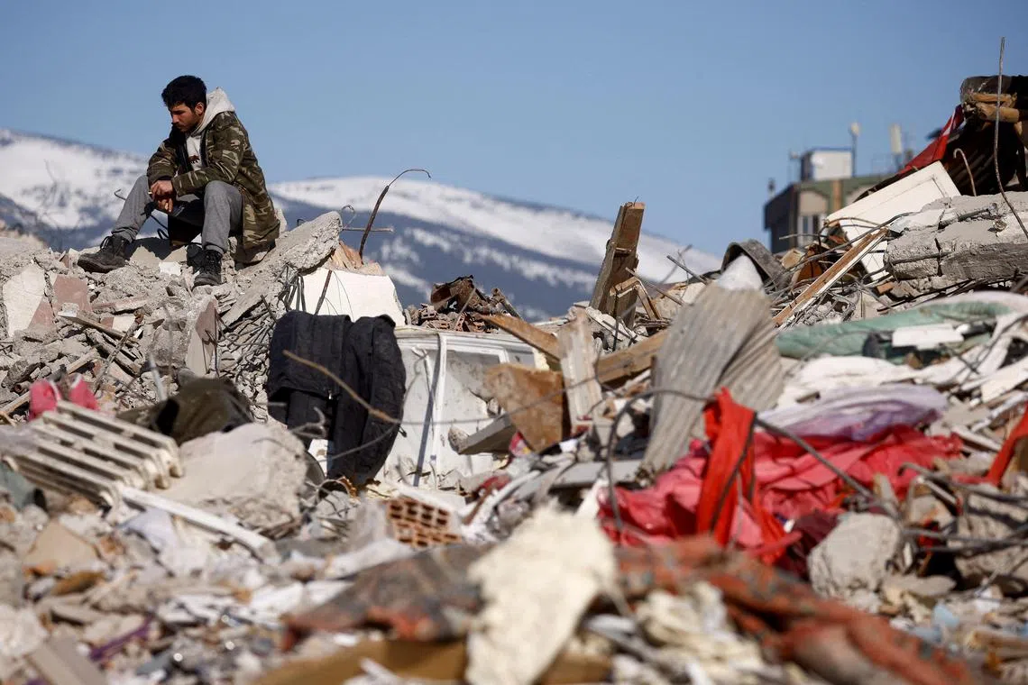 A man sits amid the rubble of buildings, in the aftermath of a deadly earthquake, in Kahramanmaras, Turkey, on Feb 11, 2023.