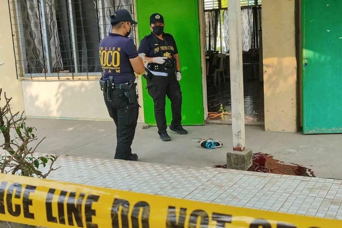 Police investigators stand next to a pool of blood after a shooting incident at a classroom entrance in a high school in Banga town, South Cotabato, in southern island of Mindanao on September 18, 2026. A student killed at least two people at a school in the southern Philippines on Friday before turning the gun on himself, officials told AFP, the country's third deadly campus attack since June. (Photo by AFP)