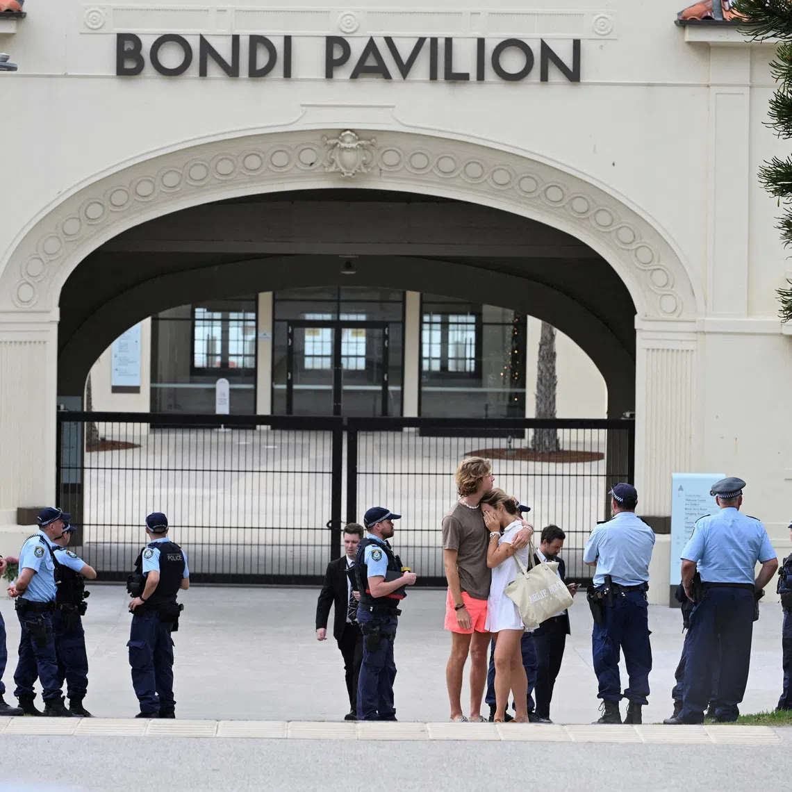 FILE PHOTO: Two people embrace as police officers stand guard outside Bondi Pavilion following the attack on a Jewish holiday celebration at Sydney's Bondi Beach, in Sydney, Australia, December 15, 2025. REUTERS/Flavio Brancaleone