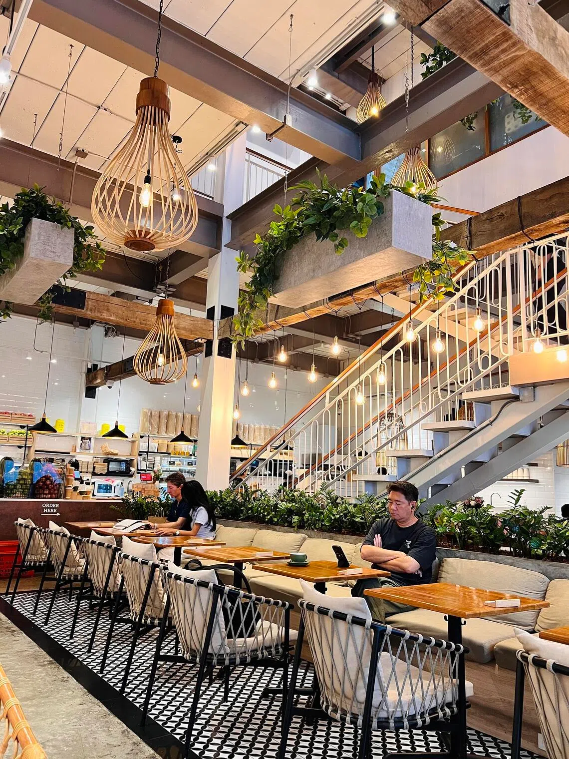 Three levels of blond oak furniture, cream cushions, and lush greenery create an inviting Scandinavian lounge at Bartels Asok.