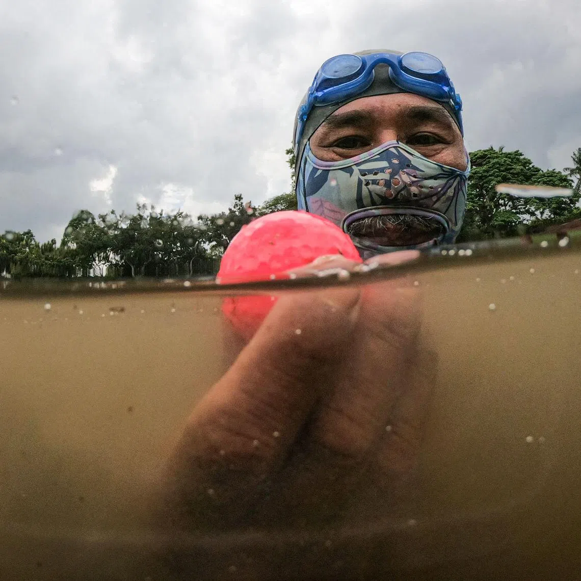 In this picture taken on November 11, 2024, Sumadi Ibrahim, 51, shows a golf ball he found inside a pond at a course in Shah Alam, on the outskirts of Kuala Lumpur. After two decades plunging Malaysian seas to defend his country, navy frogman Sumadi Ibrahim has retired to the golf course -- diving water hazards to retrieve mis-hit balls to make a living. For 22 years Sumadi served in the Royal Malaysian Navy, deployed aboard ships patrolling the shark-riddled waters off the Pacific archipelago. (Photo by Mohd RASFAN / AFP) / To go with MALAYSIA-GOLF-ENVIRONMENT-DIVING, FOCUS by Isabelle LEONG