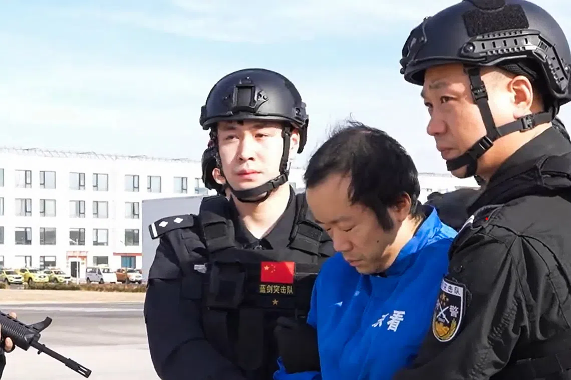 Guards escorting accused scam boss Chen Zhi (centre) off a plane in Beijing. Chen was extradited to China from Cambodia.