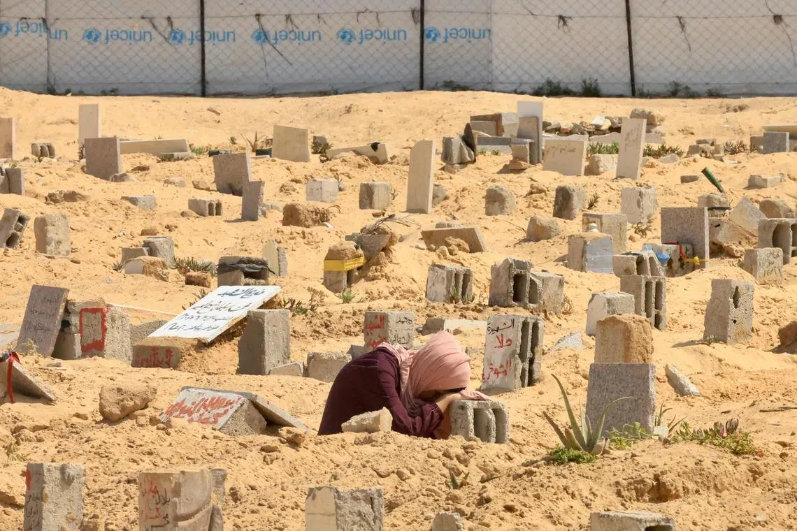 A Palestinian woman mourns over the grave of a relative in Khan Yunis in the southern Gaza Strip on June 16, 2025.  