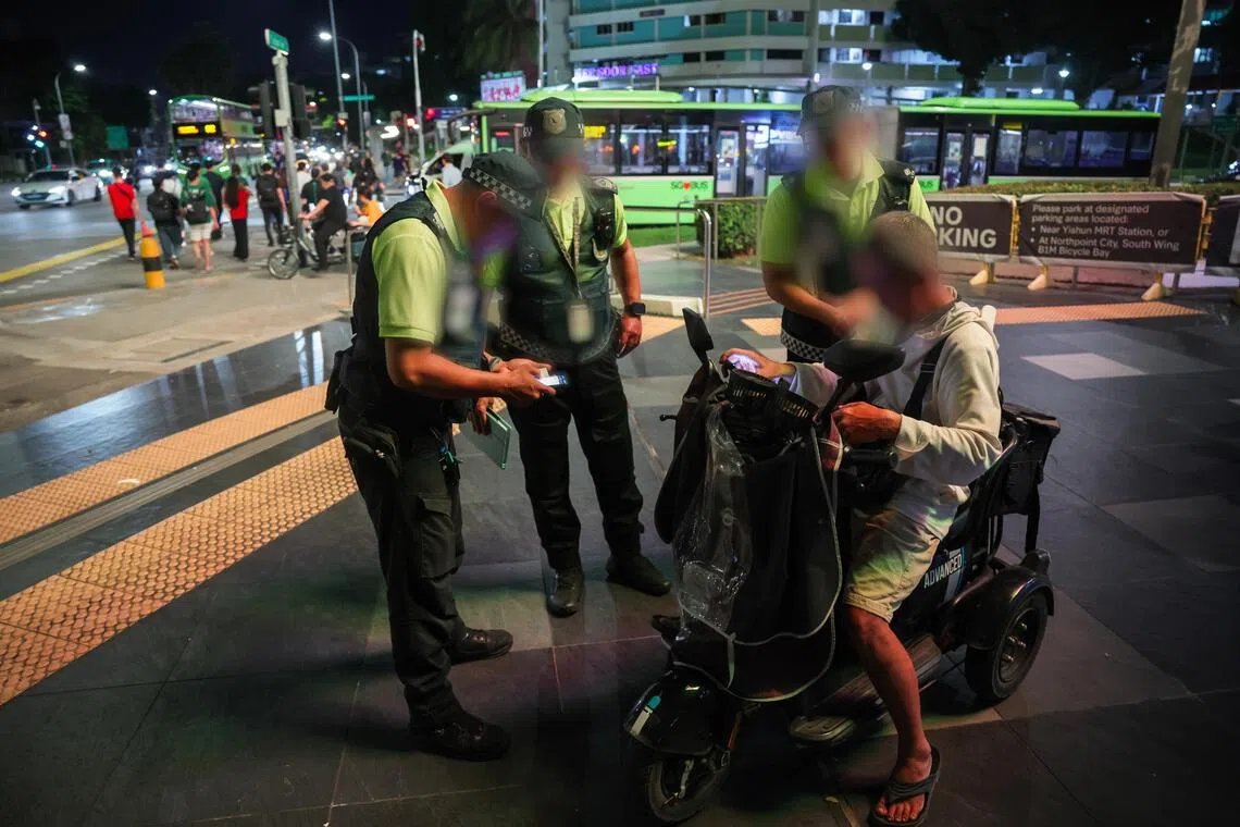 LTA enforcement officers verifying the registration details of a PMA during the enforcement checks in Northpoint City in Yishun on Aug 3.