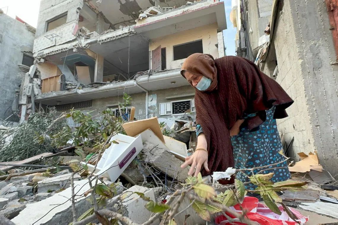 A Palestinian woman inspects the remains of a house hit by an Israeli strike, in Khan Younis, in the southern Gaza Strip.