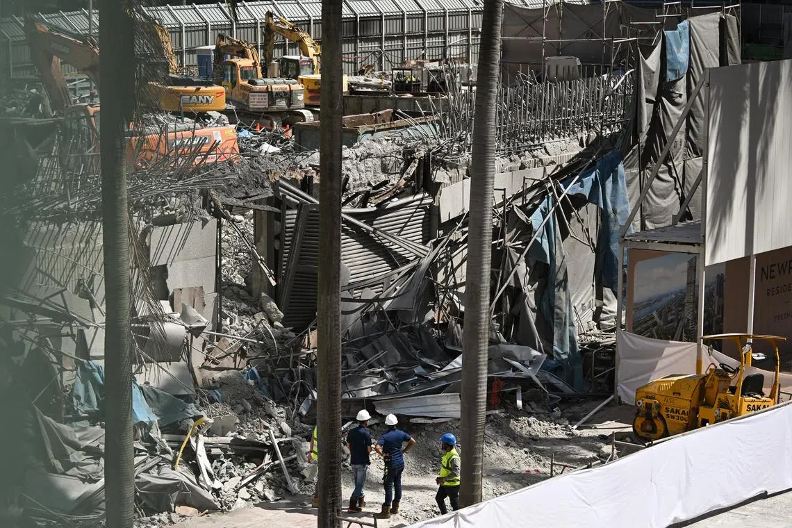 MOM officers (in blue top and white helmets) investigating the worksite accident where one worker was killed after part of the Fuji Xerox Towers building in Tanjong Pagar collapsed during demolition works.