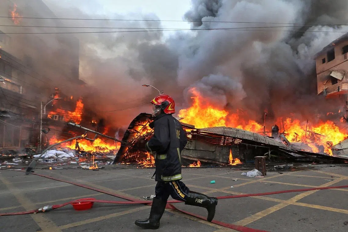 A firefighter runs to extinguish a fire that broke out in a clothing market in Dhaka on April 4, 2023. 