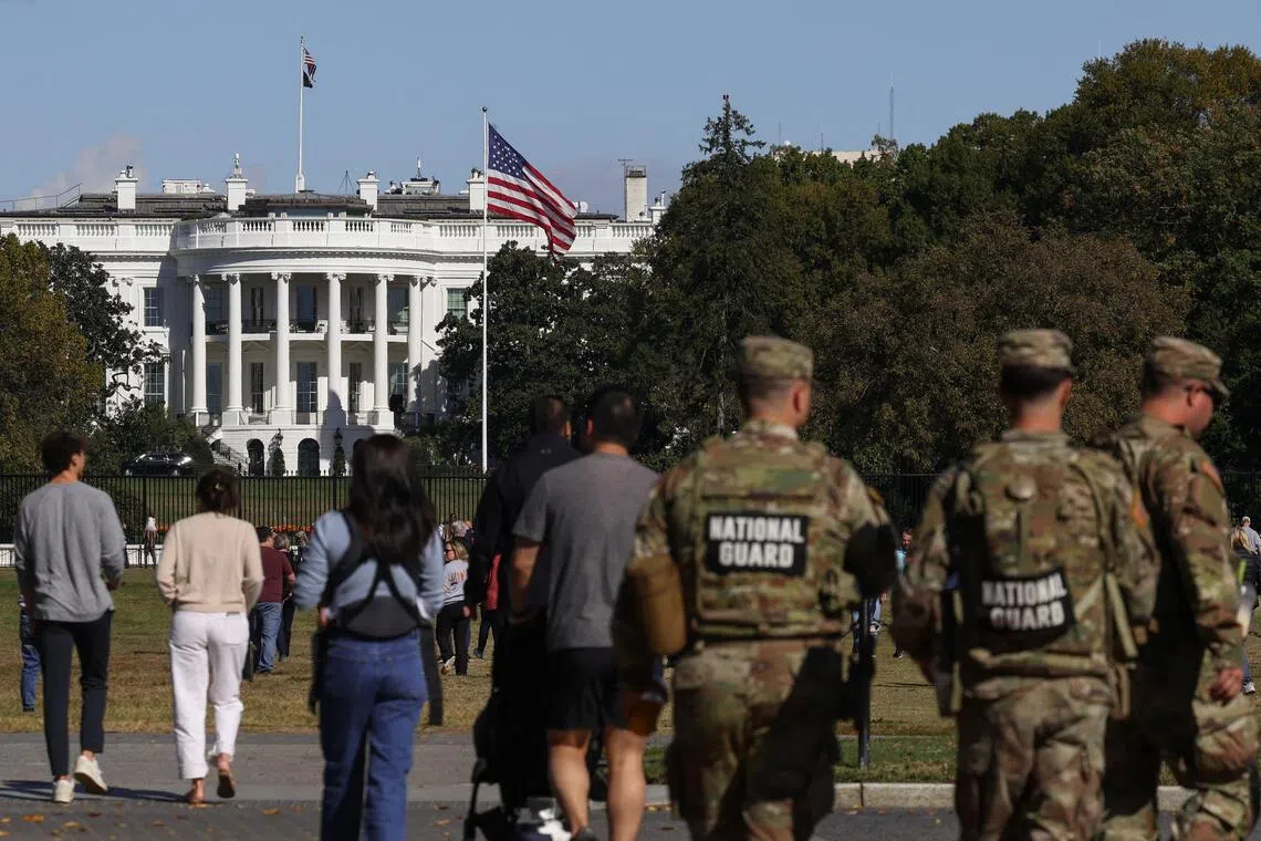 National Guard members and visitors walking near the White House in Washington, weeks into the ongoing US government shutdown, on Oct 22.