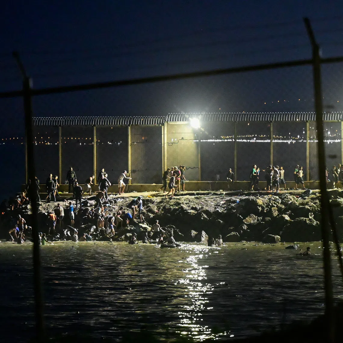 Migrants from Morocco cross into Ceuta by sea and gather near the border fence between the Spanish enclave of Ceuta and Morocco, as seen from Ceuta, Spain, July 30, 2026. REUTERS/Fabian Bimmer