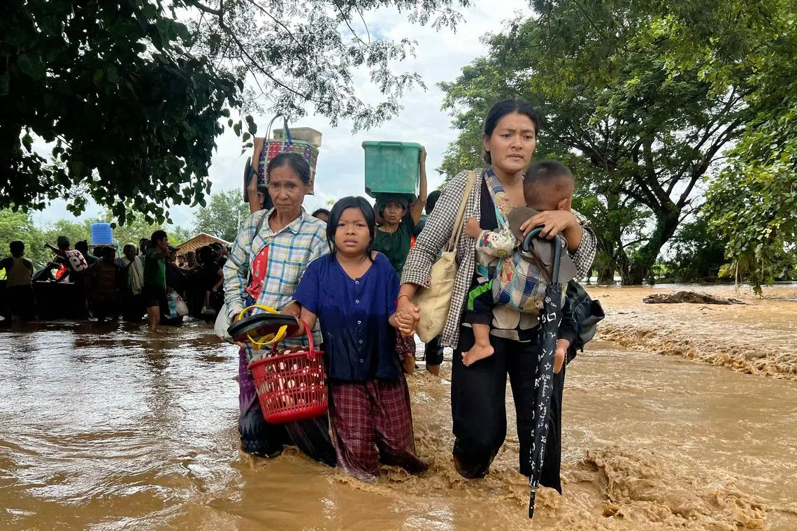 ]Residents walk through flood waters in Pyinmana in Myanmar's Naypyidaw region on Sept 13, 2024.