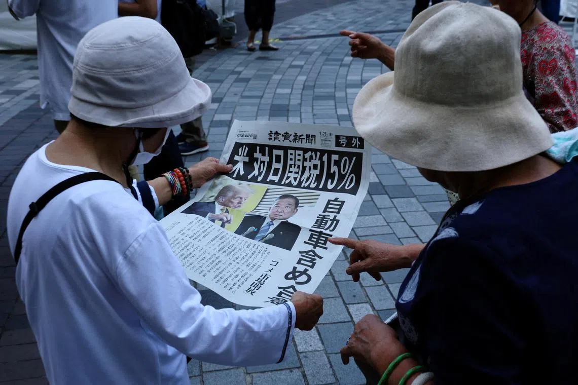 People reading a Yomiuri Shimbun news report in Tokyo on July 23 about the tariff agreement between the US and Japan.