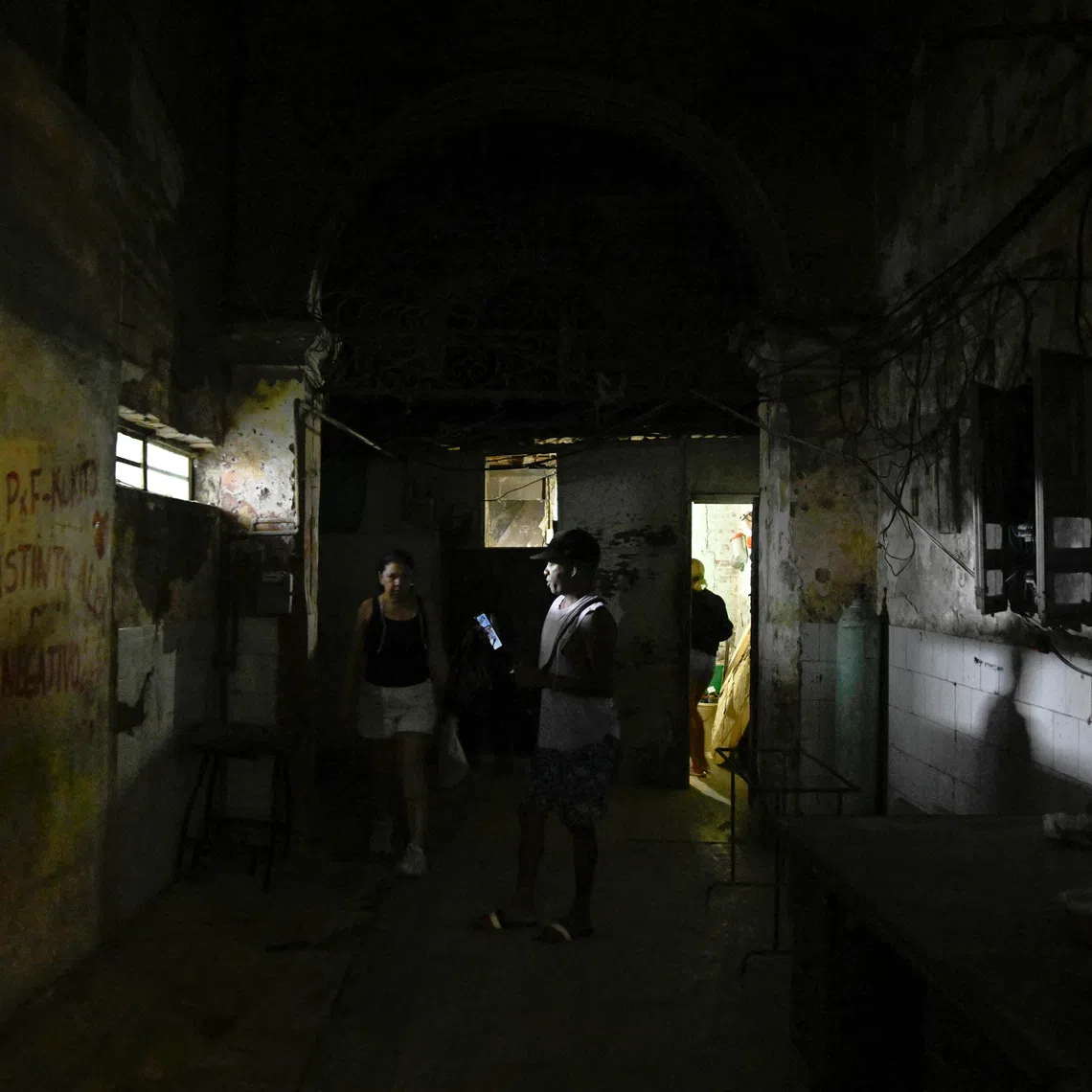 People walk through a hallway after power was restored following a partial collapse of the electrical grid that left much of western Cuba in the dark, in Havana, Cuba, December 3, 2025. REUTERS/Norlys Perez