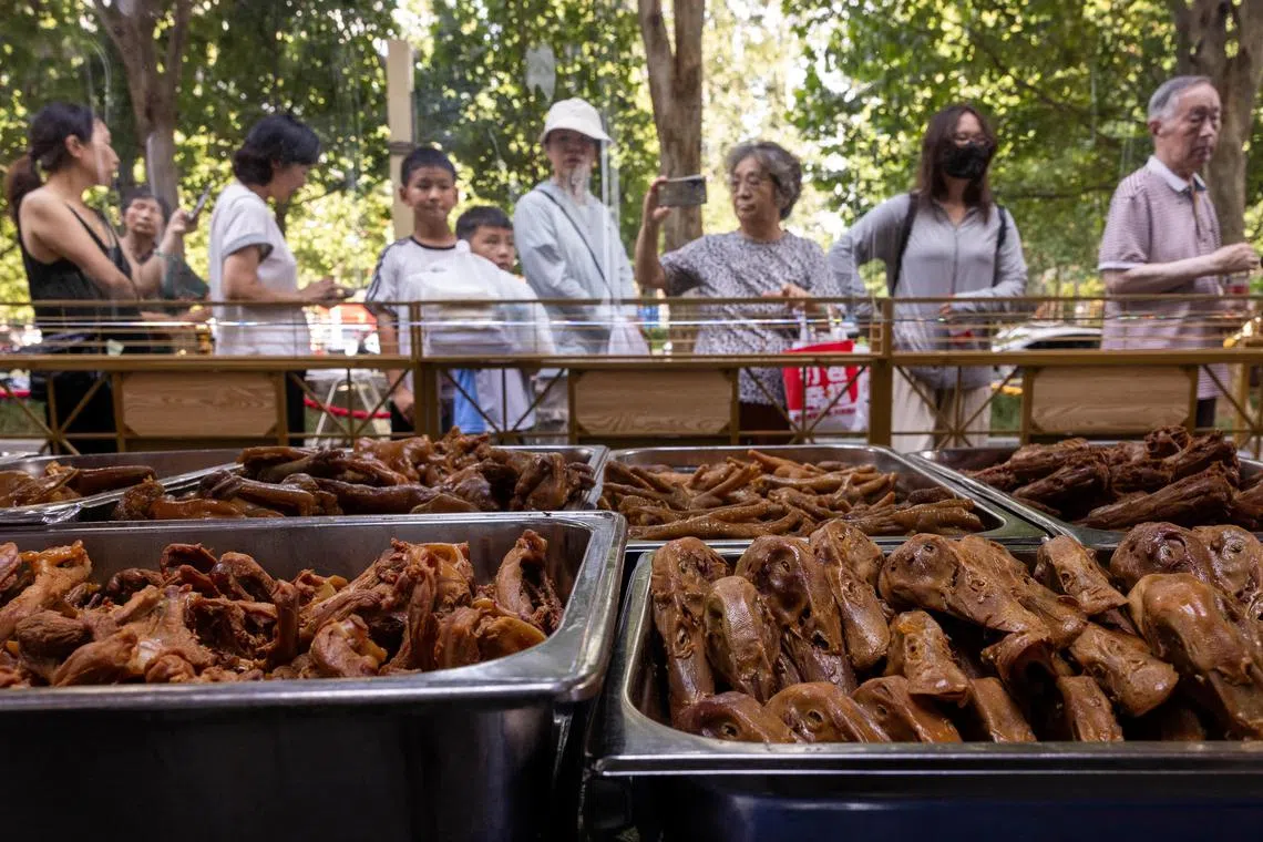 People queue at a setup of stalls selling food to passersby next to Beiyuan Grand Hotel in Beijing, China, on Aug 11.