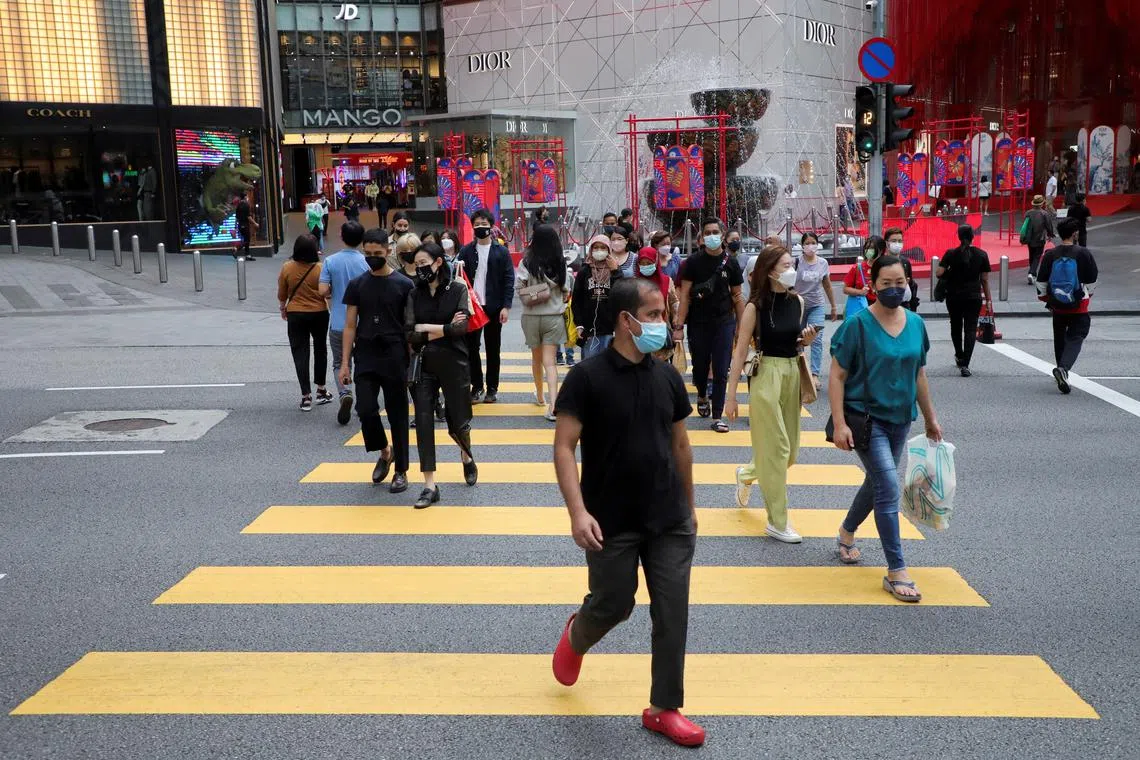 FILE PHOTO: People wearing protective face masks cross a street in Malaysia's Bukit Bintang shopping district in Kuala Lumpur, Malaysia, January 19, 2022. REUTERS/Hussain Hasnoor/File Photo