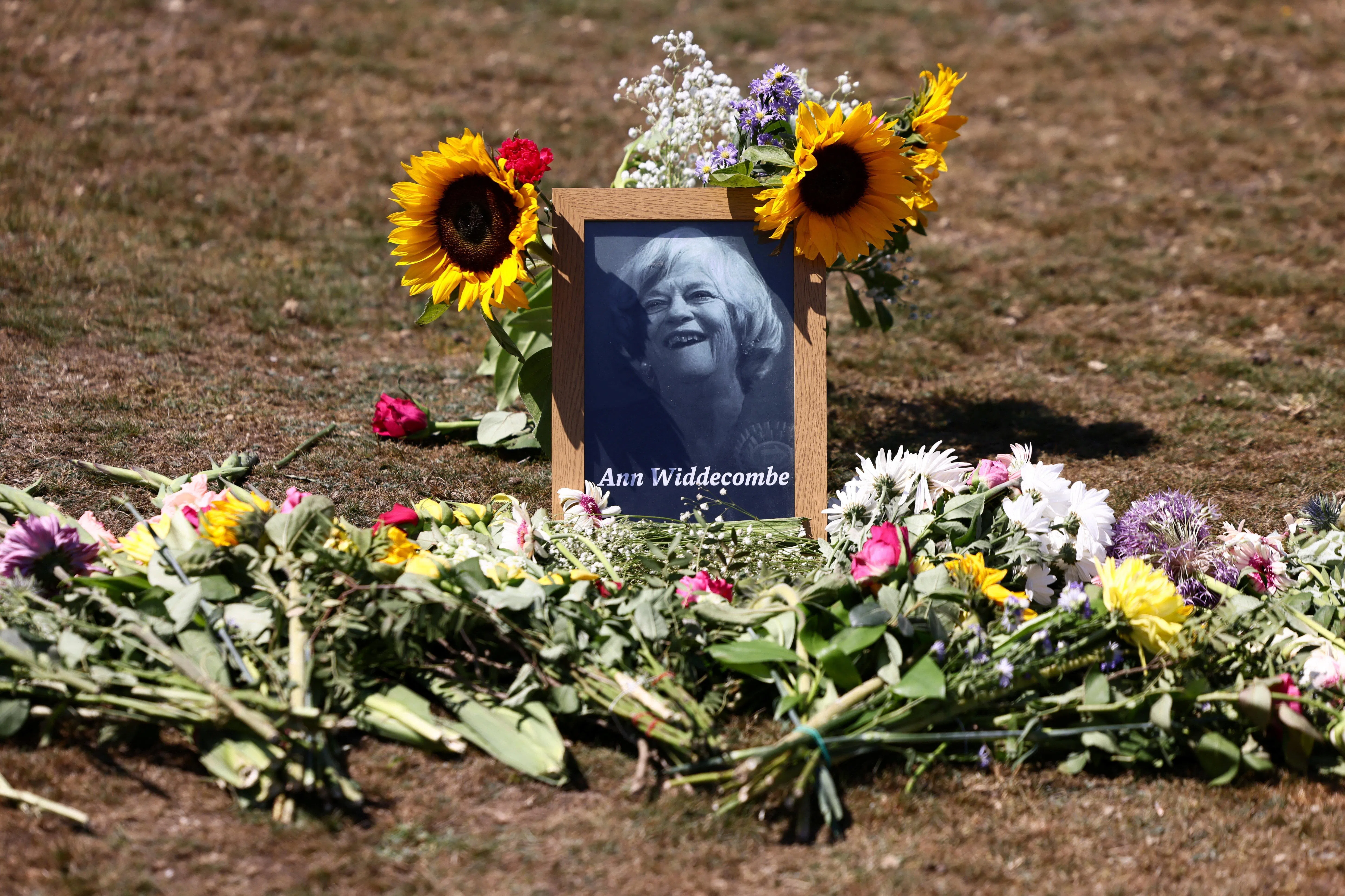 Flower tributes lie next to a portrait of 78-year-old former government minister Ann Widdecombe after she was found dead, as the police investigation continues, in Dartmoor National Park in Haytor, Britain, July 11, 2026. REUTERS/Jack Taylor