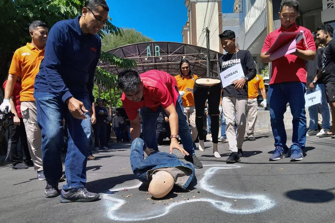 This picture taken on July 27, 2023 shows Indonesian police conducting a re-enactment of a robbery and murder amid a spate of violent crimes by 'begal' -- a specialist criminal that has gained notoriety for their brutality -- in Semarang, Central Java. A spate of violent robberies by machete-wielding thieves in Indonesia has drawn coded calls from prominent politicians for them to be killed-on-sight by police, in comments condemned by rights groups as condoning extrajudicial murders. (Photo by DAFFA RAMYA KANZUDDIN / AFP) / To go with AFP story Indonesia-crime-justice,FOCUS by Hafiz Gunawan and Jack Moore