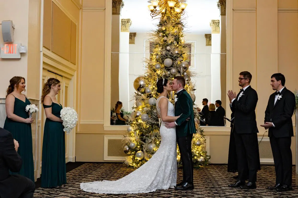 Danielle Maier and Steven Mullen share a kiss during their wedding ceremony at the Historic Hotel Bethlehem, which has 31 Christmas trees and specializes in holiday nuptial packages, in Bethlehem, Pa., Dec. 9, 2023. For couples looking to re-create a Hallmark Christmas movie setting, the Historic Hotel Bethlehem has become a popular destination for holiday nuptials. (Hannah Beier/The New York Times)