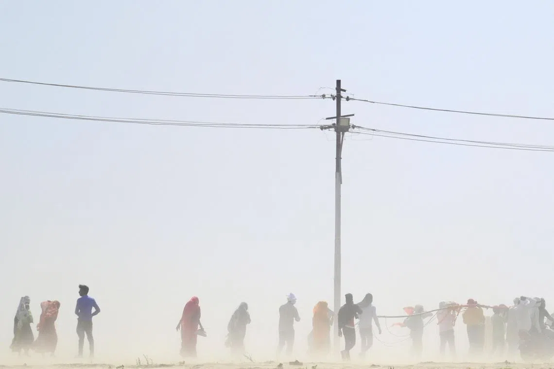 People walk through a dust storm on a hot summer day in Prayagraj on April 18, 2023.